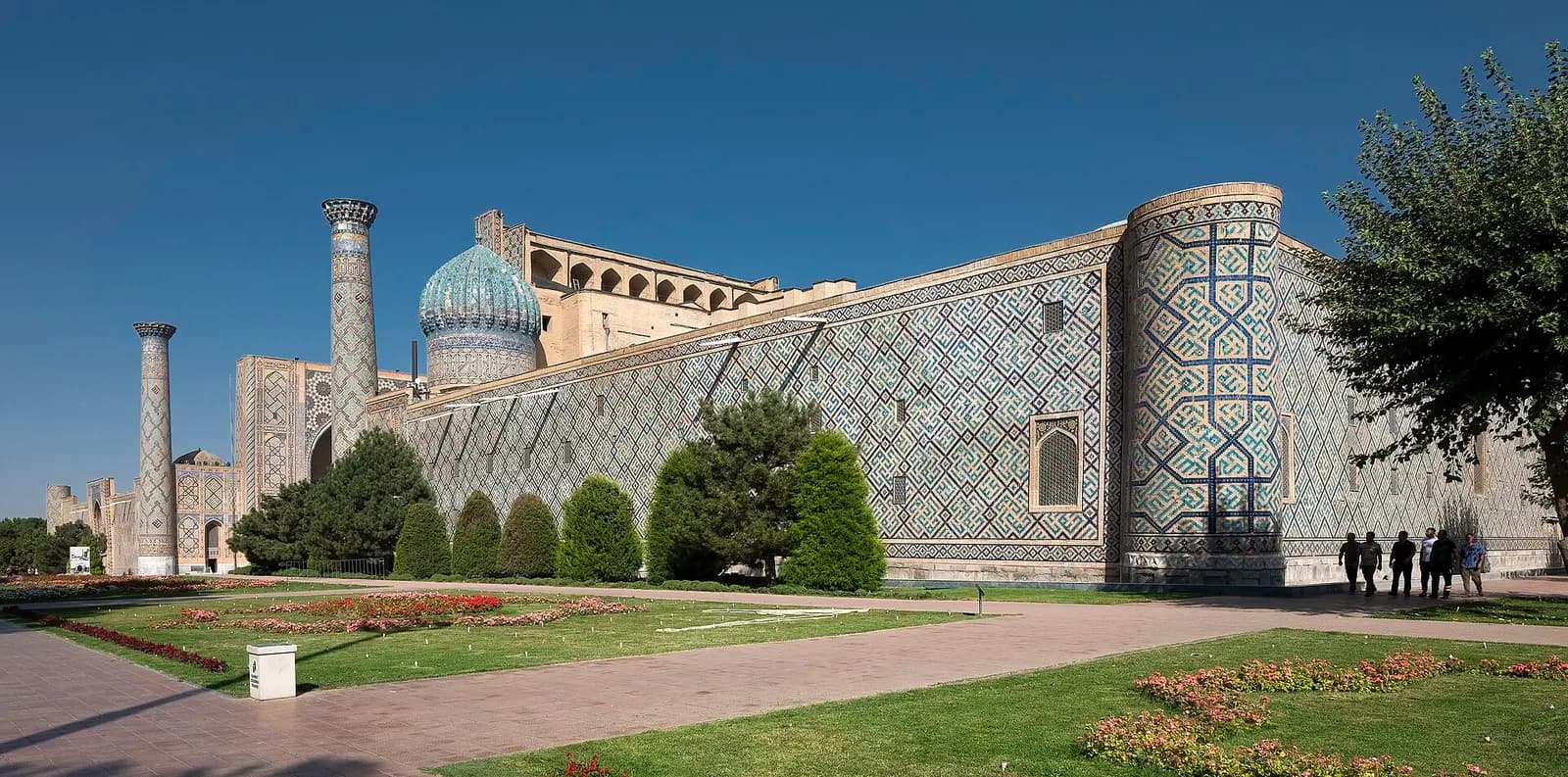 The tiled side wall and minarets of the Ulugh Beg Madrasa with the ribbed blue dome of the Sher-Dor Madrasa beyond, Registan, Samarkand