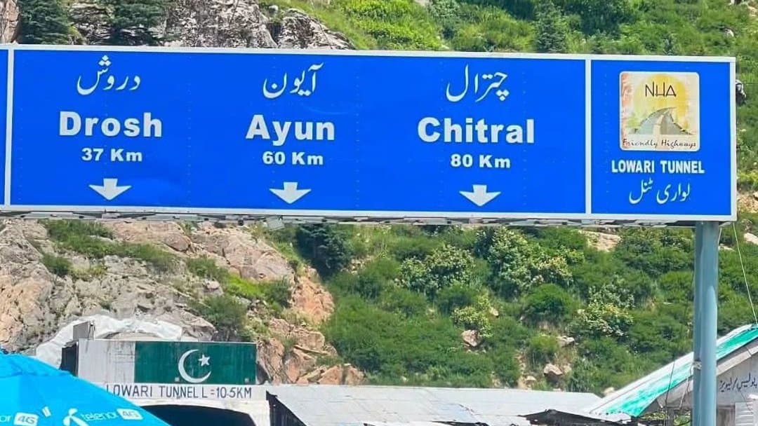The Lowari Tunnel portal on the road into Chitral, under a highway sign for Drosh, Ayun and Chitral