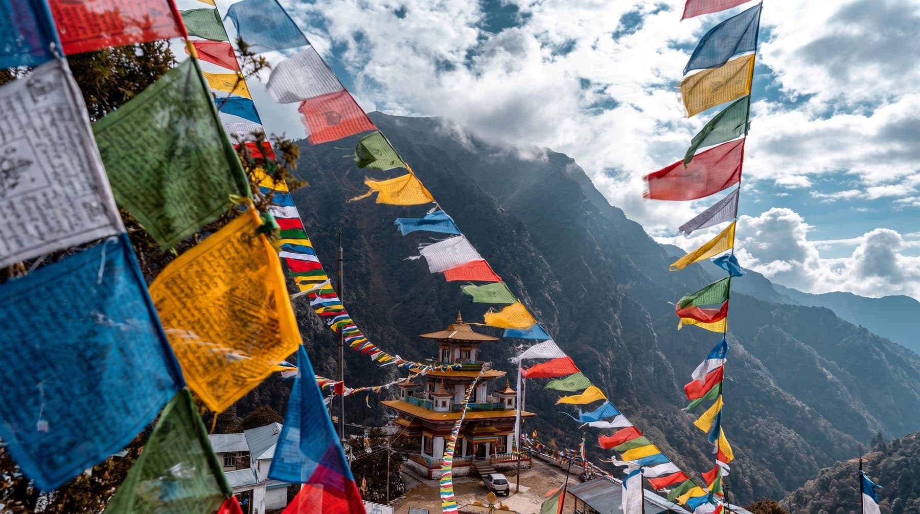 Strings of prayer flags framing a Buddhist monastery on a forested Himalayan mountainside