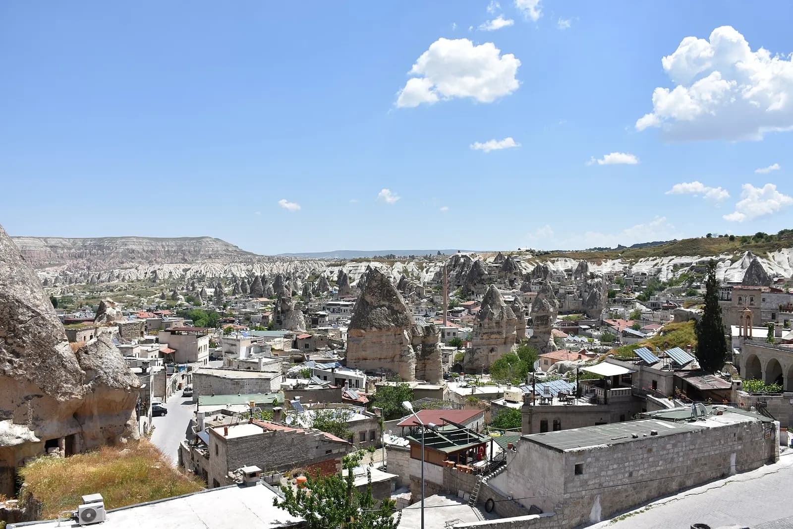 Göreme town in Cappadocia, its stone houses built among cone-shaped fairy chimneys, with eroded white valleys and a flat-topped ridge beyond