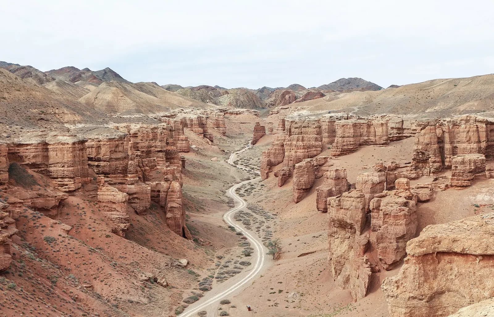 Red sandstone pillars on both sides of a dry gravel track in the Valley of Castles, Charyn Canyon, Kazakhstan