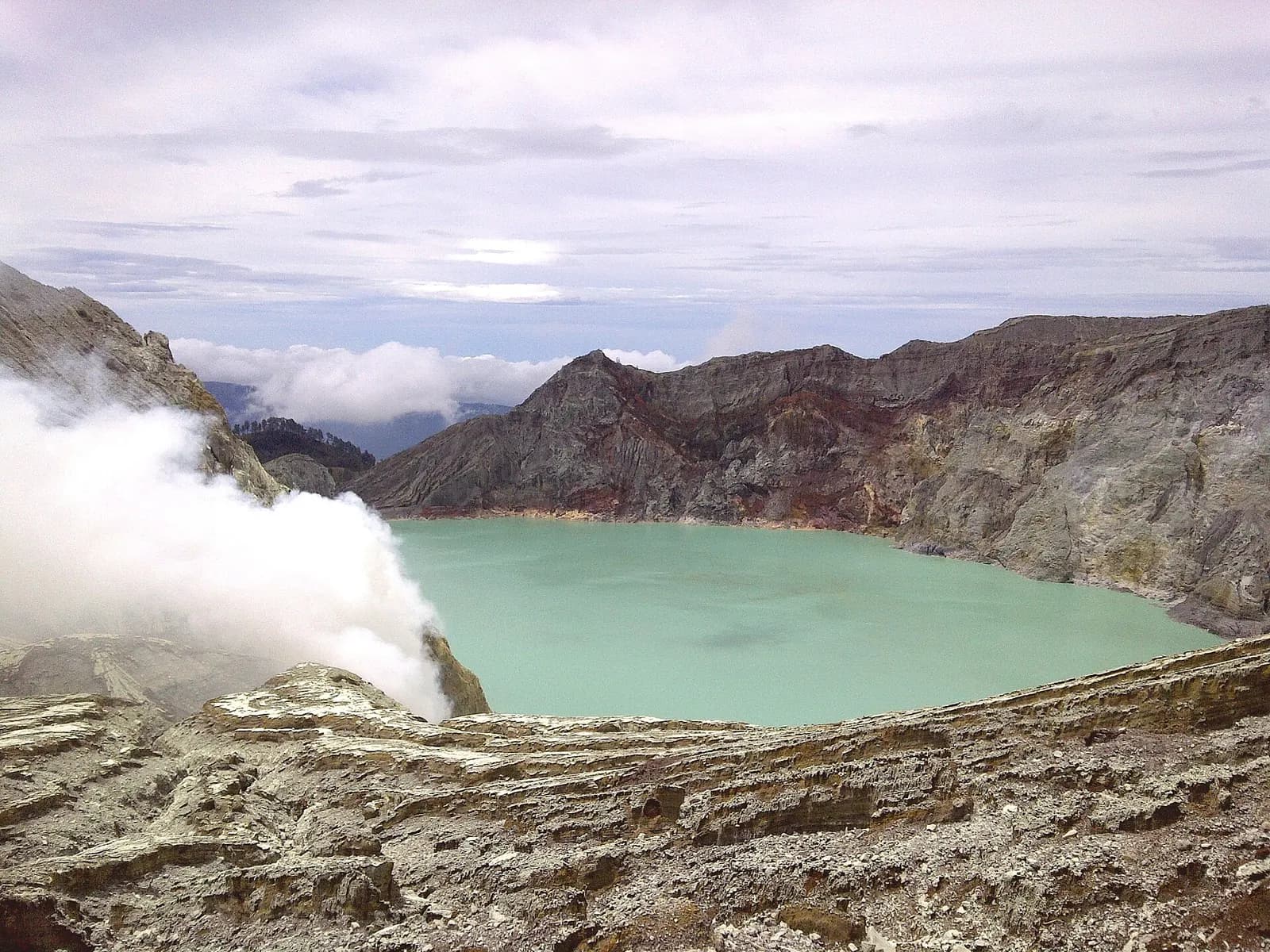 Sulphur smoke drifting over the turquoise acid lake inside the Ijen crater, East Java