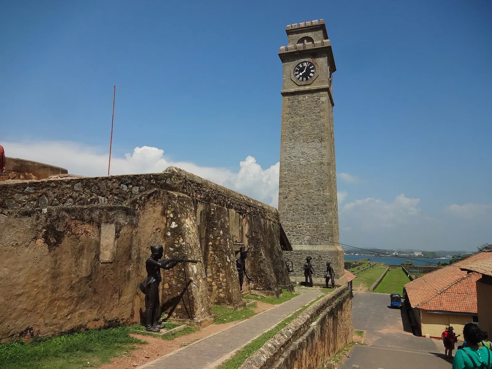 Weathered stone ramparts and the clock tower at Galle Fort, with the harbour and the sea beyond under a blue sky